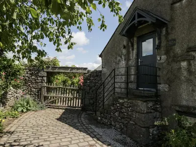 an old stone building with a door and a fence at Treacle in Carnforth