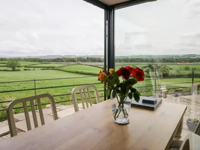 a vase of flowers on a table with a view at Lindeth Croft in Carnforth