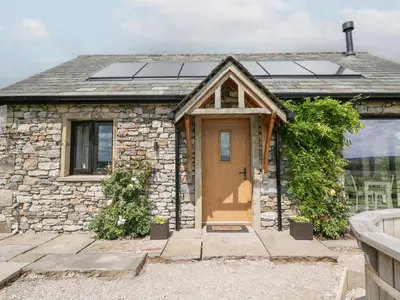 a stone cottage with a brown door and windows at Lindeth Croft in Carnforth
