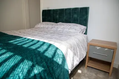 a bed with a green headboard and a wooden night stand at Balmoral Stays 4 - First Floor in Blackpool