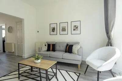 a living room with a couch and a table and a chair at 3 Bed House 9 mins walk to Anfield Sleeps 7 in Liverpool