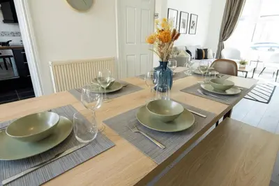 a dining room table with plates and glasses on it at 3 Bed House 9 mins walk to Anfield Sleeps 7 in Liverpool