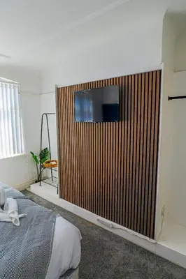 a bedroom with a television on a wooden wall at Contractor Stays, Newly Renovated, Free Parking, Sleep 7 in Wallasey