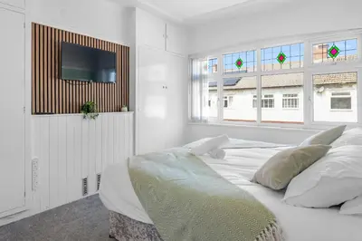 a white bedroom with a bed and a flat screen tv at Contractor Stays, Newly Renovated, Free Parking, Sleep 7 in Wallasey