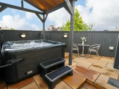 a hot tub on a patio with a table at Lakes View Apartment 1 in Carnforth