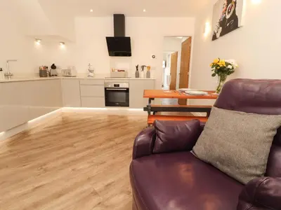 a living room with a couch and a kitchen at Lakes View Apartment 1 in Carnforth
