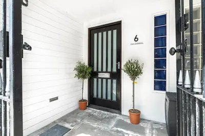 a black door on a white house with two potted plants at Modern unique duplex apartment in town centre in Lytham St Annes