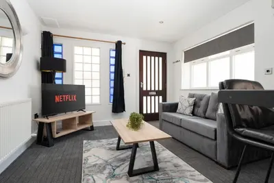 a living room with a couch and a tv at Modern unique duplex apartment in town centre in Lytham St Annes
