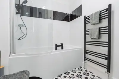 a white bathroom with a shower and a tub at Modern unique duplex apartment in town centre in Lytham St Annes