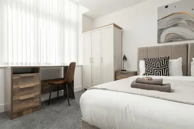 a bedroom with a large bed with a desk and a chair at Modern unique duplex apartment in town centre in Lytham St Annes