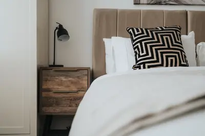 a bedroom with a bed and a wooden night stand at Modern unique duplex apartment in town centre in Lytham St Annes