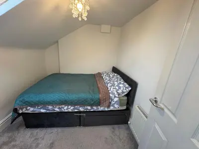 a small bed in a small room with a chandelier at Bay Walk Place in Morecambe