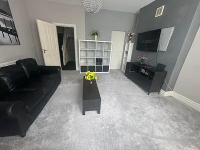 a living room with a black couch and flowers in it at Bay Walk Place in Morecambe