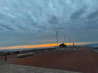a pier with benches on the beach at sunset at Bay Walk Place in Morecambe