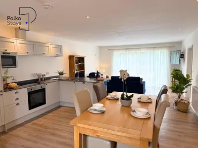 a kitchen and living room with a wooden table and a table and chairs at No 7 PolkaStays Ivy Farm Fern Cottage in Plumpton