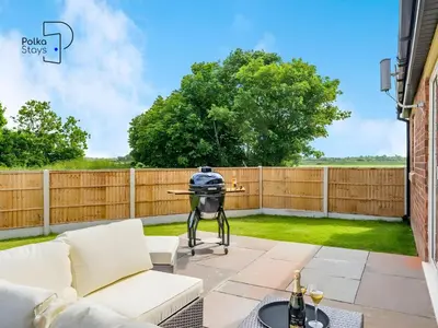 a patio with white furniture and a fence at No 7 PolkaStays Ivy Farm Fern Cottage in Plumpton
