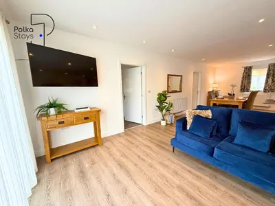 a living room with a blue couch and a tv at No 7 PolkaStays Ivy Farm Fern Cottage in Plumpton