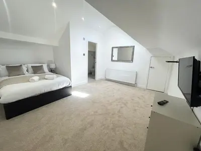 a white bedroom with a bed and a television at Stanley House - Luxury 6 Bed, Free Parking in Blackpool