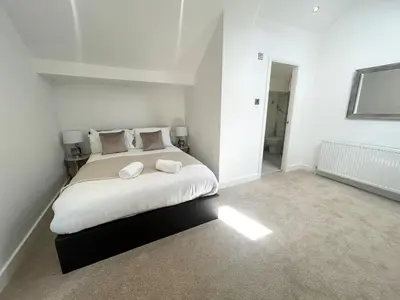 a white bedroom with a large bed with two pillows at Stanley House - Luxury 6 Bed, Free Parking in Blackpool