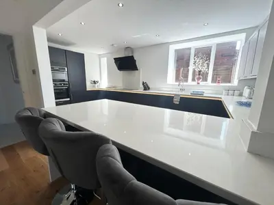 a kitchen with a white counter and chairs in it at Stanley House - Luxury 6 Bed, Free Parking in Blackpool