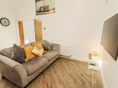 a living room with a couch and a clock on the wall at Lakes View Apartment 2 in Carnforth