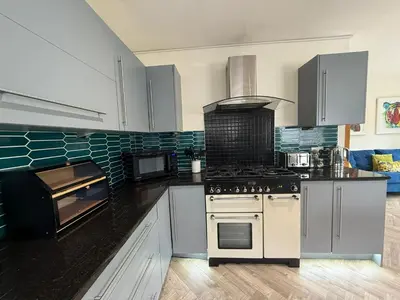 a kitchen with white cabinets and a stove top oven at The Hydeaway, Lytham St.Annes House | Free Parking in Lytham St Annes