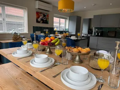 a wooden table with plates and glasses of orange juice at The Hydeaway, Lytham St.Annes House | Free Parking in Lytham St Annes