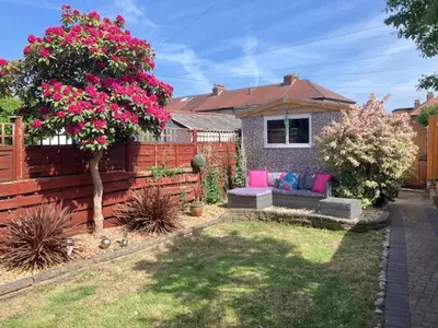 a garden with a bench and a fence with pink flowers at Palm House Lytham St Annes in Lytham St Annes