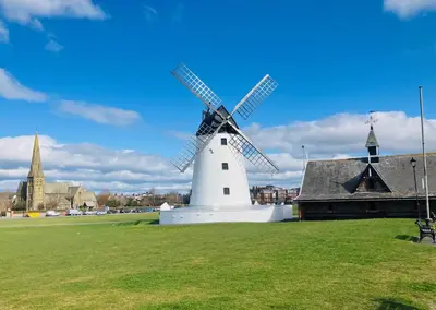 a windmill in a field next to a building at Palm House Lytham St Annes in Lytham St Annes