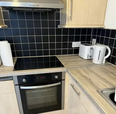 a kitchen with black tiles on the wall at City Centre Apartment in Liverpool