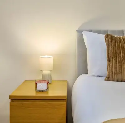 a bedroom with a bed and a nightstand with a lamp at The Red Retreat, 7 Beds, Garden, Free Parking, Contractors, Fast Wifi, Smart TV in Liverpool