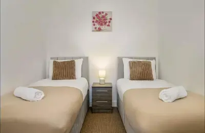 two twin beds in a room with a night stand at The Red Retreat, 7 Beds, Garden, Free Parking, Contractors, Fast Wifi, Smart TV in Liverpool
