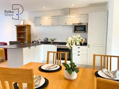 a kitchen with white cabinets and a wooden table at No 6 PolkaStays Ivy Farm Orchard Suite in Plumpton