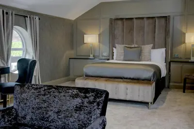 a bedroom with a king sized bed and a chair at The Eccleston Hotel; BW Signature Collection in Saint Helens