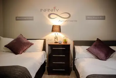 a bedroom with two beds and a lamp on a night stand at Infinity St Ives Grove- With Street Parking in Liverpool
