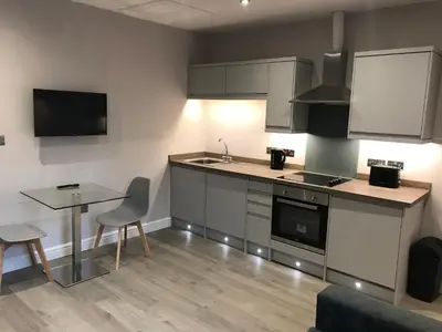 a kitchen with a sink and a table and a counter at Central 1 bed stylish apartment in Barrow in Furness