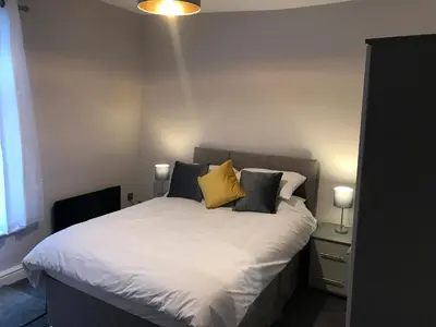 a bedroom with a bed with white sheets and yellow pillows at Central 1 bed stylish apartment in Barrow in Furness