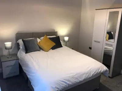 a bedroom with a bed with white sheets and yellow pillows at Central 1 bed stylish apartment in Barrow in Furness