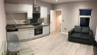a kitchen with a couch and a chair in a room at Central 1 bed stylish apartment in Barrow in Furness