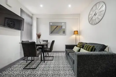a living room with a couch and a table and a clock at Anfield Nest - Air Host & Stay - 3 bed 3 bath in Liverpool