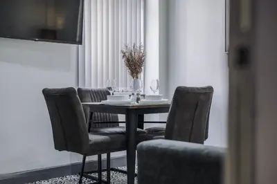 a dining room table with chairs and a table with a vase at Anfield Nest - Air Host & Stay - 3 bed 3 bath in Liverpool