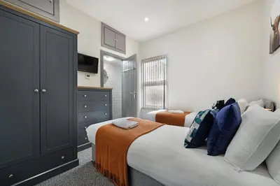 a bedroom with two beds and a television in it at Anfield Nest - Air Host & Stay - 3 bed 3 bath in Liverpool