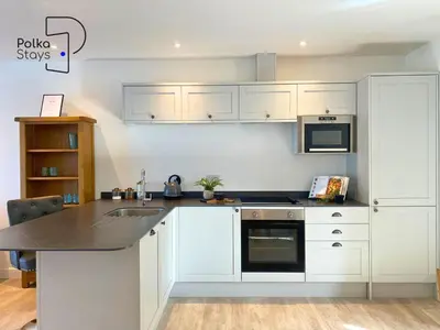 a kitchen with white cabinets and a black counter top at No 8 PolkaStays Ivy Farm Primrose Deluxe in Brown Moss Side