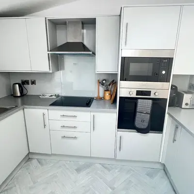 a white kitchen with white cabinets and a microwave at Thwaite Croft - Carnforth in Carnforth