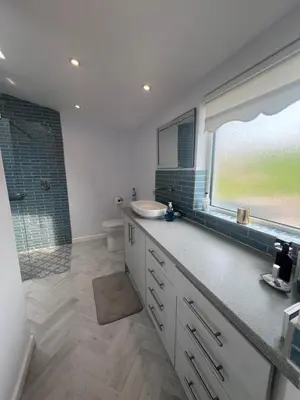a bathroom with a sink and a shower with a window at Thwaite Croft - Carnforth in Carnforth
