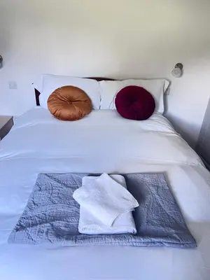 a white bed with three pillows on top of it at Thwaite Croft - Carnforth in Carnforth