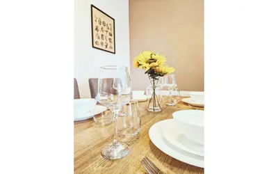 a dining room table with glasses and plates and flowers at Lodginet Stays - County View - 1BR Flat 4 in Liverpool