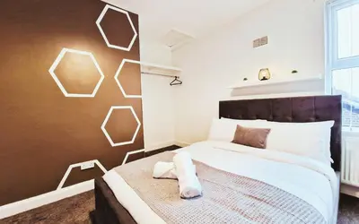 a bedroom with a bed and a wall with hexagons at Lodginet Stays - County View - 1BR Flat 4 in Liverpool