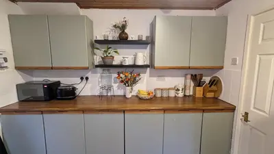 a kitchen with white cabinets and a wooden counter top at Stay your way in Huyton with Roby