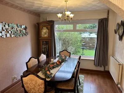 a dining room table with chairs and a large window at Stay your way in Huyton with Roby
